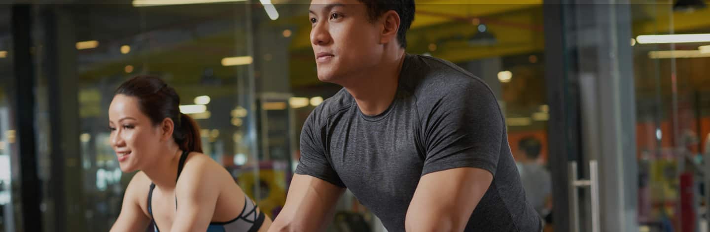 Man and woman exercising on stationary bikes.
